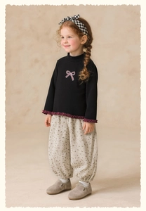 Close-up of girl clothing set with floral pants and black top with ruffle edge details