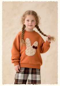 Close-up of cute rabbit floral applique on soft warm orange girl's sweatshirt
