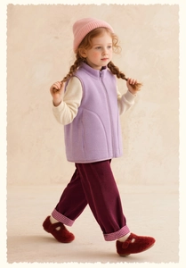Detail of girls' lilac fleece vest with warm knit sweater and red corduroy pants