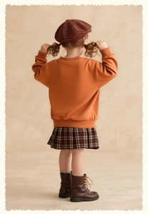 Detailed back view of a toddler girl wearing orange rabbit sweatshirt and plaid skirt
