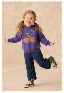 Detail of girl's purple cherry sweatshirt and striped wide-leg pants with soft knit texture