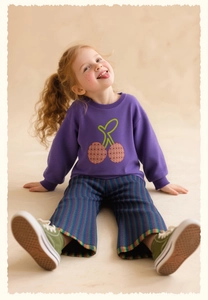 Close-up of girls' purple sweatshirt with cherry embroidery and striped wide-leg pants