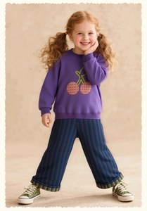Detailed view of kids' purple sweatshirt with cherry patch and striped casual pants