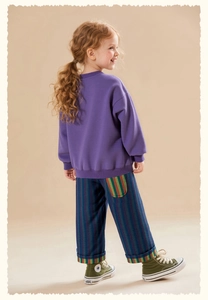 Toddler girl purple sweatshirt with multicolor striped pants and green high-top sneakers