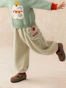 Girls mint green knit sweater with apple patches and beige corduroy trousers for autumn wear