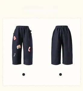 Detail view of girls' navy denim pants with colorful letter embroidery on front and back