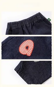 Detail view of Amila kids jeans featuring elastic waist and red checkered letter embroidery