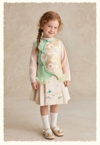 Détail d'une jupe plissée à broderie florale et gilet de style chinois pour fille