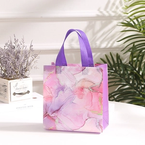 Detail of marble pattern gift bag with purple woven handles and golden fluid art texture