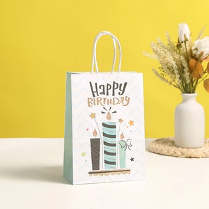 Dettaglio della borsa regalo in carta con testo Happy Birthday e motivo candela blu