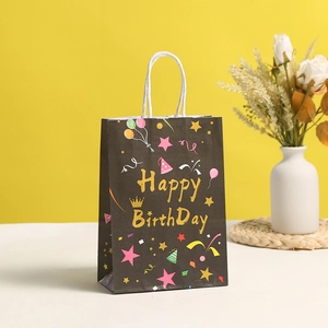 Detail of black gift bag with gold Happy Birthday text and crown motif on yellow background