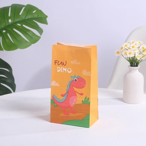 Détail du sac cadeau en papier dinosaure jaune avec motif Fun Dino sur table