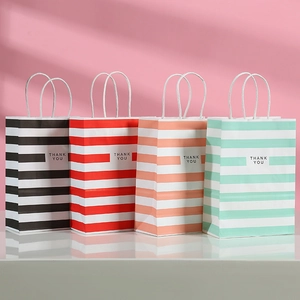 Close-up of four colorful striped kraft paper gift bags with THANK YOU logo and white handles
