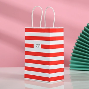 Detail of red and white striped kraft paper gift bag with white twisted rope handles