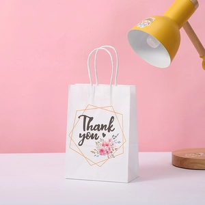Détail d'un sac cadeau blanc avec lettrage Thank You et motif floral doré élégant
