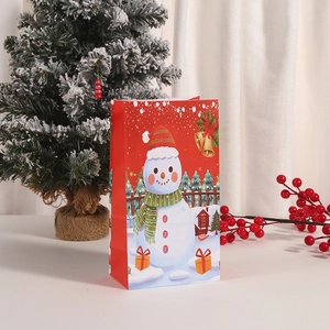 Detailed view of red Christmas paper gift bag featuring a cute snowman with festive pine