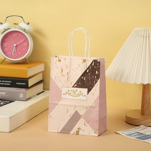 Detailed close-up of marble pattern gift bag with cotton rope handles and gold foil logo