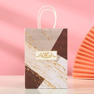 Detail of marble pattern gift bag with gold foil splatters and elegant floral tag