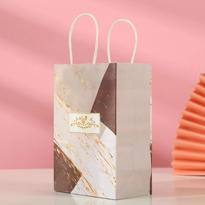 Detail of marble pattern gift bag with gold geometric design and white rope handles