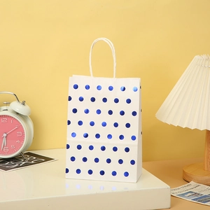Close-up of white kraft gift bag with metallic blue polka dots and sturdy rope handles