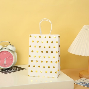 Detail of white kraft gift bag with gold foil polka dots and paper handles