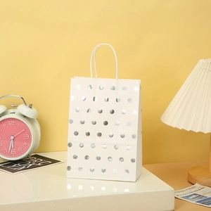 Detailed view of white paper gift bag with silver foil dots and twisted paper handles