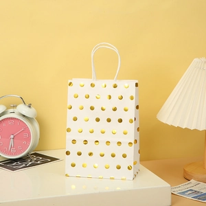 White kraft paper gift bag with metallic gold polka dots and matching white handles