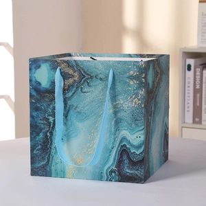 Blue marble patterned gift bag with gold ink details and woven rope handles