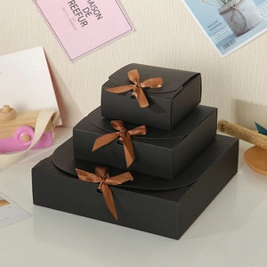 Three sizes of black square gift boxes with brown satin bows in a tiered display