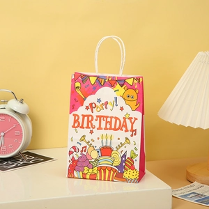 Detail of pink birthday party paper gift bag with handles and cartoon monster design