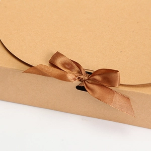 Detail of kraft paper gift box featuring a premium brown satin ribbon and bow closure