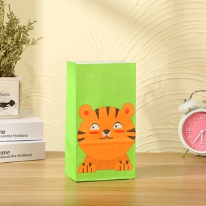 Detail of green kraft gift bag with cute cartoon tiger print on wooden table background