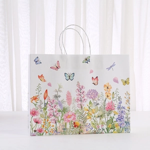 Geschenktüte aus Papier mit Blumen-Aquarell und weißen Griffen vor Vorhang-Hintergrund