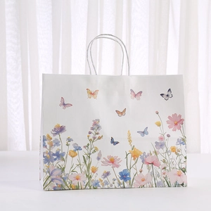 Weiße Papiertüte mit Blumen und Schmetterlingsdruck sowie weißen Kordelgriffen