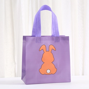 Detail of purple non-woven tote bag featuring a cute orange bunny print with white pom-pom tail