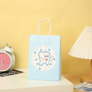 Detail of light blue baby party paper gift bag with white handles and tooth pattern