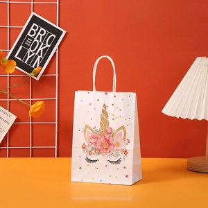 Detail of white unicorn gift bag with golden horn and pink floral patterns on orange background