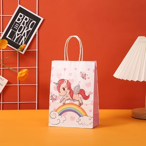 Detailed view of white and pink paper gift bag featuring a cute cartoon unicorn and rainbow