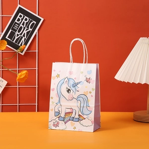 Detail of white unicorn gift bag with purple sides and rainbow stars on a desk
