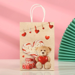 Detail of kraft paper gift bag featuring festive teddy bear with red hearts and white handle