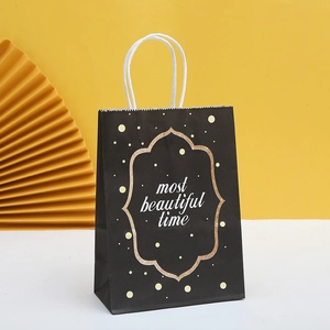 Detail of elegant black paper gift bag with golden frame and white rope handles