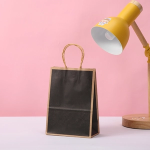 Sacchetto regalo minimalista in carta kraft nera con bordi marroni e manici intrecciati