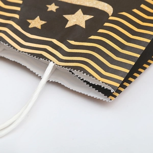 Sac cadeau en papier noir avec étoiles dorées, motifs à vagues et anses en corde blanche