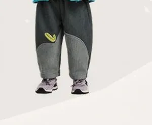 Dettaglio dei joggers bicolore grigi da bambino con toppa a foglia verde e fodera in pile
