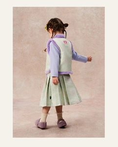 Detalle posterior de conjunto de invierno para niña con chaleco floral y falda plisada