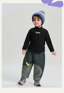 Dettaglio completo invernale bimbo con maglia a lupetto e pantaloni di velluto grigio con toppa