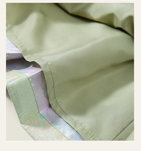 Detalle macro de ropa infantil de estilo chino con brocado floral en verde claro