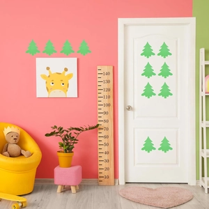 Détail de la toise en bois et des stickers muraux arbre vert dans une chambre d'enfant