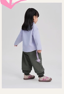 Vista posteriore di un bambino con maglia in pile viola e pantaloni verdi
