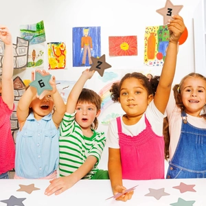 Children holding colorful star cutouts with numbers for classroom math learning